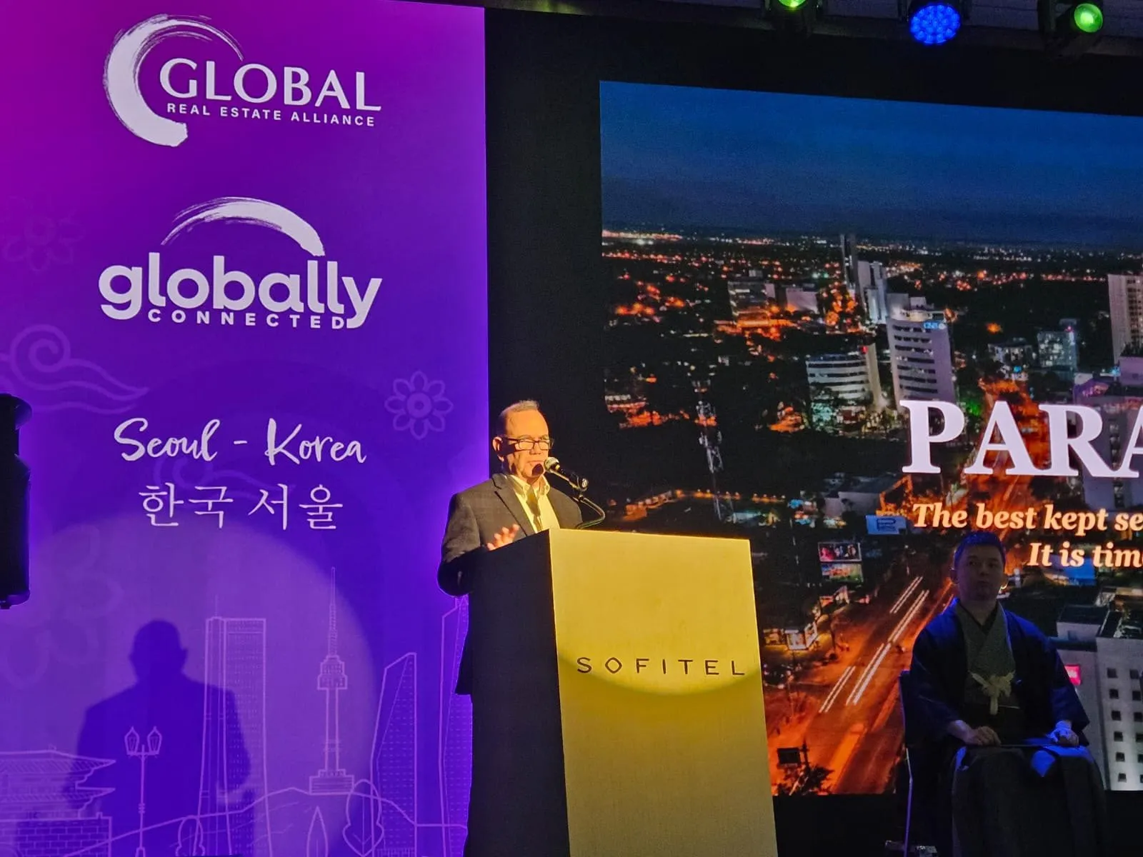 Kiko speaking at a podium at the Global Real Estate Alliance event in Seoul