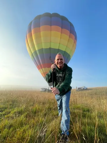 Kiko standing in a meadow beside a hot air balloon