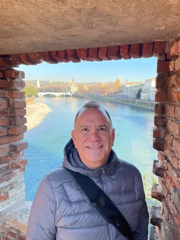 Kiko smiling through a stone window frame with a river behind him